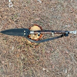 K&ouml;nnte beinhalten: Ein handgefertigter Speer mit schwarzer Klinge und einem mit Leder umwickelten Holzgriff. Der Speer liegt auf einem kleinen Holzsockel und hat einen Lederriemen. Der Speer ist etwa 76 cm lang.