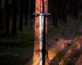 May include: A double-edged steel sword featuring a long, straight blade with a central fuller, a silver-toned crossguard with intricate detailing, and a dark brown cylindrical grip topped with a black pommel featuring a carved geometric pattern.