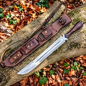 May include: A fixed-blade knife with a polished steel blade and a dark wood handle, accompanied by a brown leather sheath. The sheath features multiple integrated pouches with brass snap closures and an adjustable leather shoulder strap.