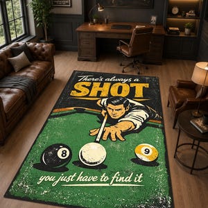 Op de afbeelding: Een rechthoekig vloerkleed met een grafische illustratie van een persoon die biljart op een groene tafel. Het ontwerp bevat de tekst "There's always a SHOT" en "you just have to find it" met een 8-bal, een 9-bal en een witte speelbal.