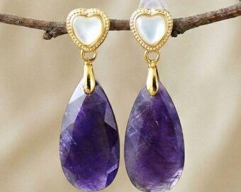 Gouden hartvormige oorknopjes met een amethist druppelvormige hanger in een gefacetteerde paarse steen.