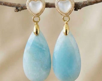 Gouden hartvormige oorknopjes met een amazoniet druppelvormige hanger in een zachtblauwe steen.