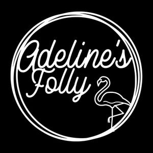 Könnte beinhalten: Weißes Logo auf schwarzem Hintergrund. Das Logo zeigt die Worte "Adeline's Folly" in Schreibschrift, umschlossen von einem doppelten weißen Kreis. Auf der rechten Seite befindet sich eine Flamingo-Umrisslinie.