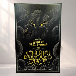 Könnte beinhalten: Eine rechteckige schwarze Schachtel für ein 78-Karten-Tarotdeck mit einer goldenen und grauen Illustration einer tentakelartigen Kreatur mit leuchtend gelben Augen. Der Text lautet From the World of H. P. Lovecraft, Cthulhu Dark Arts Tarot und Complete 78-Card Deck & Reading Guide.