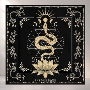 May include: Black square tapestry featuring a gold snake design. The snake is coiled above a lotus flower, with geometric shapes and celestial elements. The words "OWN YOUR POWER" are at the bottom. Decorative leaves and swirls frame the design.