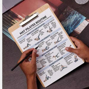 May include: A clipboard with a printed Pilates routine guide. The guide features illustrated exercises targeting core strength, flexibility, and muscle tone. The text includes exercise names like "Pelvic Tilt" and "The Hundred". A hand holds a pen, pointing to the guide.