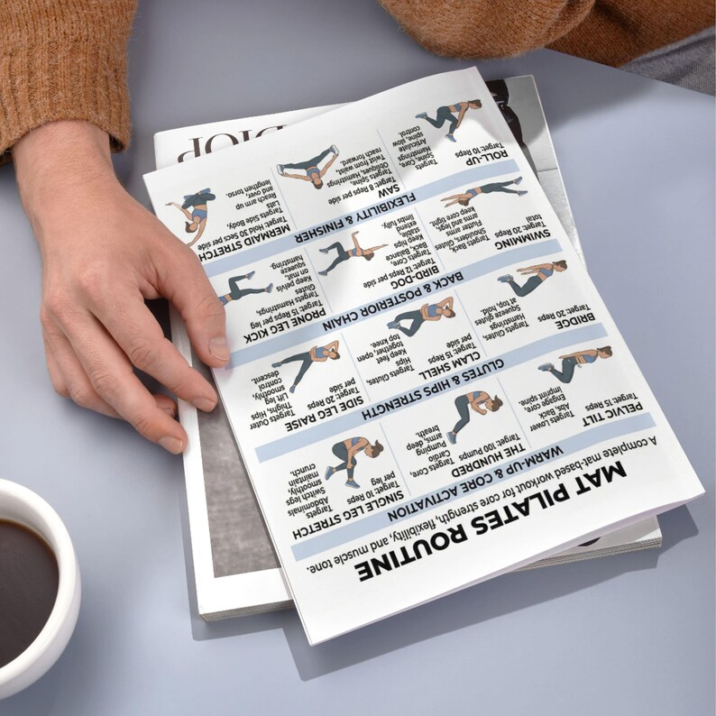 May include: A person's hand holding a printed Pilates routine guide. The guide features illustrated exercises for core strength, flexibility, and muscle tone. The routine includes exercises like the Hundred, Pelvic Tilt, and Single Leg Stretch.