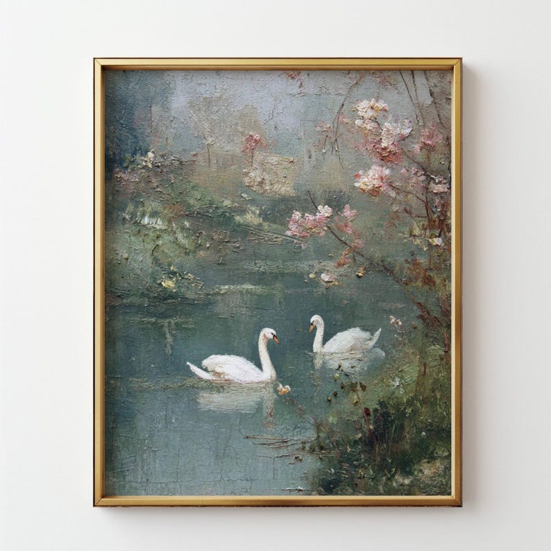 May include: An antique framed painting depicts two white swans gracefully gliding on a tranquil lake. The artwork features a soft color palette of greens, blues, and pinks, with a gold-colored frame. The painting evokes a serene, natural scene.
