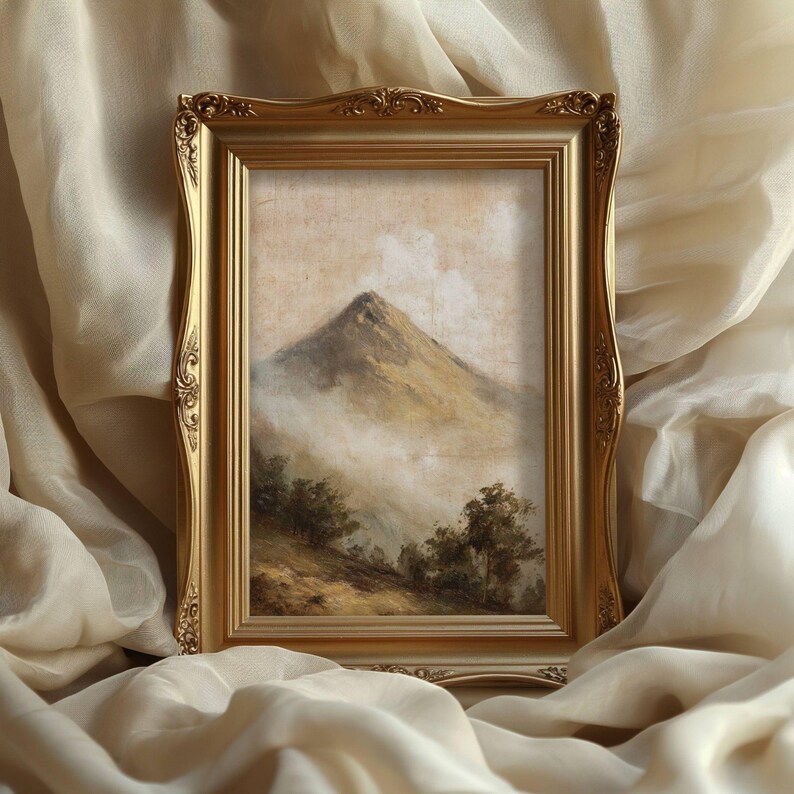 May include: A landscape painting in a gold ornate frame, depicting a mountain peak emerging from the mist. The artwork features a mountain with trees and a cloudy sky, rendered in muted earth tones. The frame has decorative detailing.