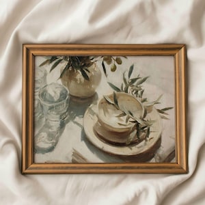 May include: A framed still life painting depicting a cream vase with olive branches, a clear glass, and a stack of plates with a bowl. The painting has a soft, neutral colour palette and a warm, golden frame.