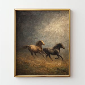 Op de afbeelding: Een ingelijst schilderij toont twee paarden die over een veld galopperen. E&eacute;n paard is bruin, de ander is donkergrijs. Het kunstwerk heeft een vintage esthetiek met een gouden lijst en een bewolkte lucht.