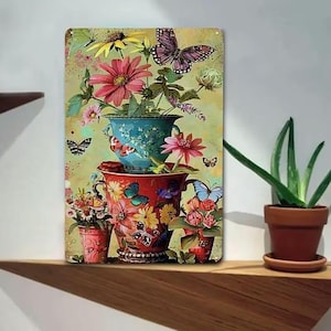 Peut inclure: Panneau décoratif en métal représentant un arrangement floral avec des fleurs roses, jaunes et rouges dans des pots bleus et rouges. Des papillons de différentes couleurs sont dispersés autour des fleurs, sur fond vert clair.