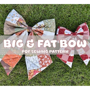 Może przedstawiać: Dwie duże, pikowane kokardy z patchworkowym wzorem są prezentowane na zielonej trawie. Kokardy są w odcieniach czerwieni, pomarańczy, zieleni i brązu. Tekst na zdjęciu brzmi "BIG & FAT BOW PDF SEWING PATTERN."