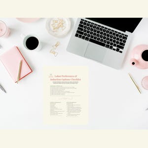 May include: A top-down view of a workspace with a laptop, pink teapot, mug of coffee, pink notebook, and a document titled "Labor Preferences & Induction Options Checklist." Gold pens, paperclips, and a candle are also present.