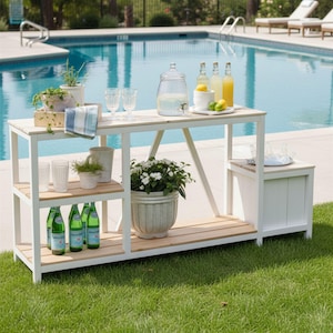 Könnte beinhalten: Eine weiße Outdoor-Bar mit Holzplatte und Regalen, neben einem Swimmingpool. Die Bar enthält Gläser, Wasserflaschen und einen großen Wasserspender. Topfpflanzen und Zitronen sorgen für Farbe. Die Bar steht auf einem grünen Rasen.