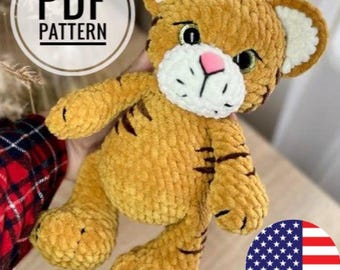May include: A handmade plush tiger with a soft, textured appearance. The tiger has a white muzzle, pink nose, and black stripes. The image includes a circular graphic with the text "PDF PATTERN".