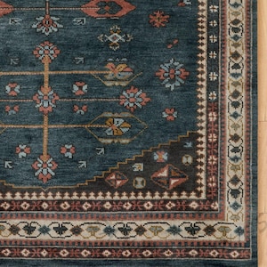 May include: A section of a teal-colored area rug with an intricate, geometric pattern. The rug features floral and geometric motifs in shades of orange, blue, and brown. A detailed border frames the design, adding to its traditional aesthetic.