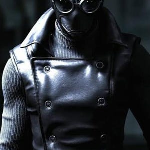 May include: A black leather-like double-breasted vest with six buttons worn over a grey ribbed sweater. The outfit includes a matching black leather-like headpiece with prominent circular goggles featuring silver rims and a central vertical seam.