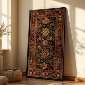 May include: A framed rug with a detailed, traditional pattern. The rug has a dark teal base with gold, red, and orange decorative elements. The black frame contrasts with the rug's colours. The rug is leaning against a cream-coloured wall.