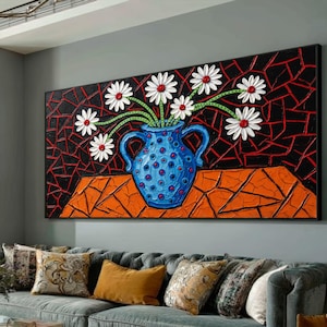 Op de afbeelding: Een rechthoekig wandkunstwerk met een gestructureerde blauwe vaas met rode stippen, gevuld met witte madeliefjes met rode harten. De achtergrond bestaat uit een zwart-rood geometrisch mozaïekpatroon op een gestructureerd oranje oppervlak.