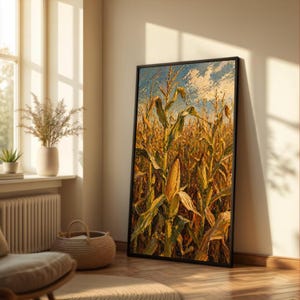 Puede incluir: Pintura al óleo enmarcada que representa un campo de maíz bajo un cielo azul con nubes blancas. La obra de arte presenta pinceladas detalladas y colores cálidos, mostrando los tallos dorados de maíz y una mazorca madura. La pintura está apoyada contra una pared en una habitación bien iluminada.