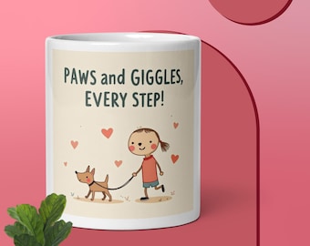 Könnte beinhalten: Weiße Keramik-Tasse mit dem Text "PAWS and GIGGLES, EVERY STEP!". Die Tasse zeigt eine Cartoon-Illustration eines Mädchens, das einen Hund ausführt, mit verstreuten Herzen. Die Tasse steht auf einer rosa Oberfläche.