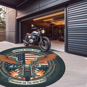 May include: A round rug with a motorcycle graphic, American flag, and eagle wings. The rug has the text "AMERICAN BIKER SPIRIT" and "FREEDOM ON THE OPEN ROAD". A motorcycle is parked in front of a garage.