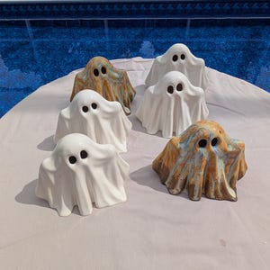 Peut inclure: Plusieurs figurines de fantômes en céramique. Les fantômes sont blancs et marbrés orange et bleu. Chaque fantôme a deux trous noirs pour les yeux et un design de drapé. Idéal pour Halloween.