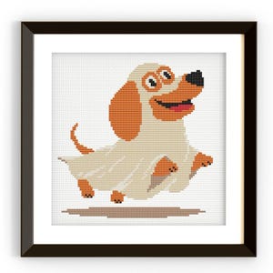 Op de afbeelding: Kruissteekkunst van een cartoonhond in een spookkostuum, met oranje oren en een zwarte neus. De hond lacht met een roze tong en het spookkostuum is gebroken wit. Het kunstwerk is ingelijst in een zwarte vierkante lijst.