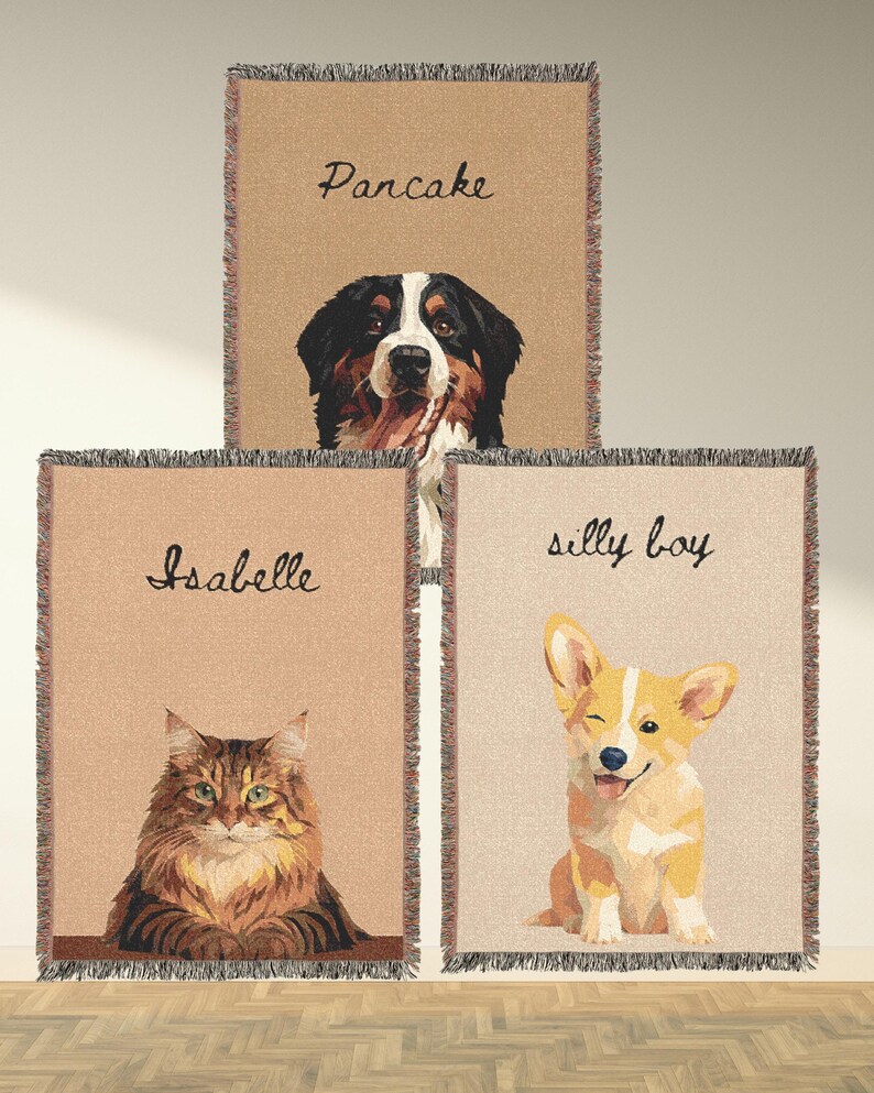 May include: Three beige throw blankets with fringed edges, each featuring a pet portrait and a name. The top blanket shows a Bernese Mountain Dog with the name "Pancake." The middle blanket has a cat named "Isabelle." The bottom blanket displays a winking corgi labeled "silly boy."