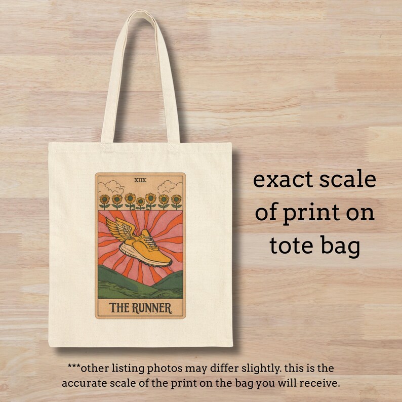 May include: Cream-colored tote bag featuring a tarot card design. The card depicts a yellow running shoe with wings, set against a backdrop of sunflowers and a rising sun. The text "THE RUNNER" is below the image. The text "exact scale of print on tote bag" is also visible.
