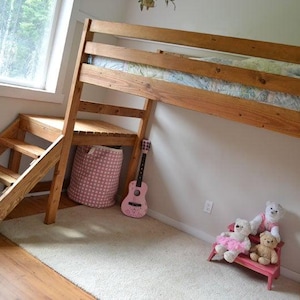 May include: A wooden loft bed with a built-in staircase and a small desk area. A pink guitar leans against the wall, and a pink and white patterned storage basket sits below the desk. Two teddy bears sit on a small pink bench.