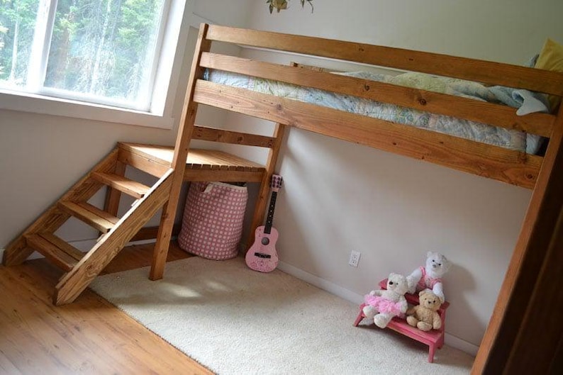 May include: A wooden loft bed with a built-in staircase and a small desk area. A pink guitar leans against the wall, and a pink and white patterned storage basket sits below the desk. Two teddy bears sit on a small pink bench.