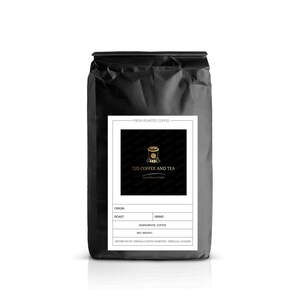 Puede incluir: Una bolsa negra de café recién tostado con una etiqueta blanca. La etiqueta presenta el texto "TJD Coffee and Tea" y un logotipo de taza de café dorada. La bolsa también incluye campos para origen, tueste, molido, ingredientes y peso neto.