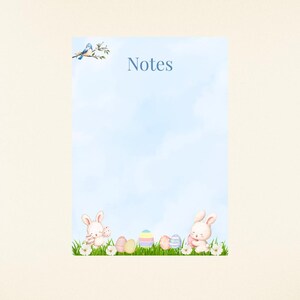 May include: A light blue notepad with the word "Notes" in the center. The bottom of the notepad features a watercolor illustration of Easter bunnies, eggs, grass, and flowers. Two blue birds are perched on a branch in the upper left corner.