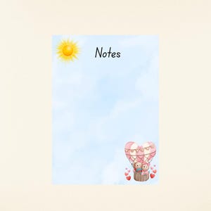 May include: A notepad with a light blue watercolour background, a yellow sun illustration, and the word "Notes" in black. A hot air balloon with two teddy bears and red hearts is at the bottom.
