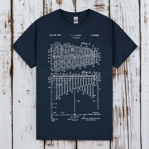 Könnte beinhalten: Ein dunkelblaues Kurzarm-T-Shirt mit einer weißen technischen Patentzeichnung eines Vibraphons. Die Grafik enthält den Text June 30, 1964, C. G. Musser, 3,138,986, Vibraphone, Fig. 1, Fig. 2 und Clair Omar Musser.