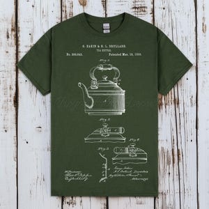 Puede incluir: Una camiseta verde oscuro con un diagrama blanco de una tetera, con otros diagramas y texto. El texto dice: "G. Dakin & H. L. Drullard. TEA KETTLE. Patentado el 19 de marzo de 1889."