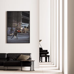 K&ouml;nnte beinhalten: Ein gerahmter Kunstdruck zeigt ein tanzendes Paar auf der Stra&szlig;e. Der schwarze Rahmen umgibt das Bild eines Mannes und einer Frau in Bewegung. Die Szene spielt in einer urbanen Umgebung, mit Geb&auml;uden und Stra&szlig;enmarkierungen im Hintergrund.