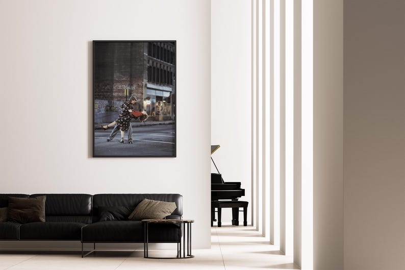 K&ouml;nnte beinhalten: Ein gerahmter Kunstdruck zeigt ein tanzendes Paar auf der Stra&szlig;e. Der schwarze Rahmen umgibt das Bild eines Mannes und einer Frau in Bewegung. Die Szene spielt in einer urbanen Umgebung, mit Geb&auml;uden und Stra&szlig;enmarkierungen im Hintergrund.