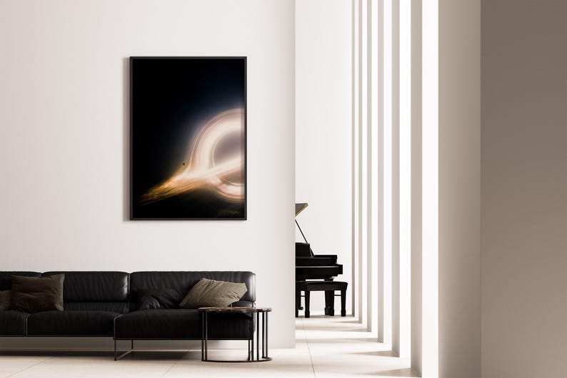 May include: A framed art print depicting a black hole with a bright, glowing ring of light against a dark background. The artwork hangs on a white wall above a black leather sofa. A black piano is visible in the background.