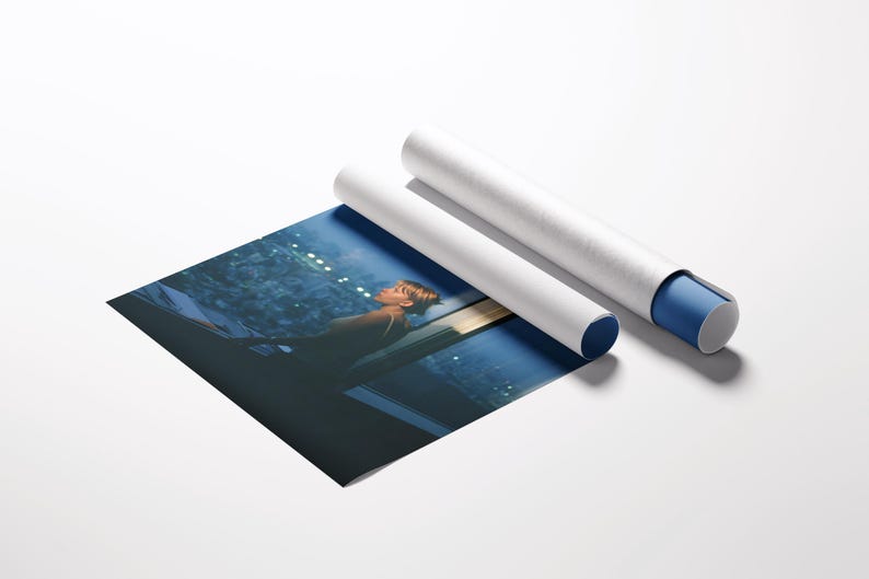May include: A rolled-up art print with a blue and white protective tube. The print depicts a person looking out a window at night. The print is partially unrolled, revealing the image. The background is white.