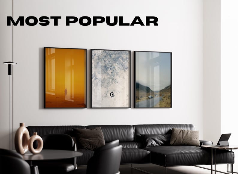 Puede incluir: Tres impresiones art&iacute;sticas enmarcadas cuelgan sobre un sof&aacute; seccional de cuero negro. Las impresiones presentan escenas abstractas y de paisajes. El texto "MOST POPULAR" se muestra encima de la obra de arte. Una mesa negra, sillas y una l&aacute;mpara de pie completan el moderno sal&oacute;n.