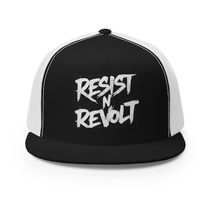 May include: A black and white trucker hat featuring a solid black front panel with the white text RESIST N REVOLT in a distressed, brush-stroke font. The cap includes a black flat brim and white mesh side and back panels with a button on top.