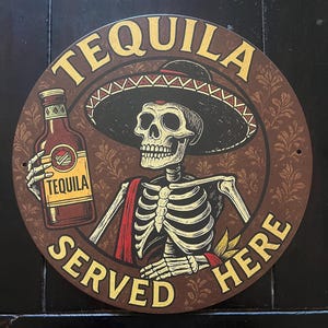 Puede incluir: Letrero redondo de metal marrón con las palabras "TEQUILA SERVED HERE" en letras doradas. El letrero presenta un esqueleto con un sombrero y sosteniendo una botella de tequila. El fondo tiene un patrón floral.