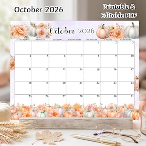 May include: A printable and editable PDF calendar for October 2026. The grid features a white background with watercolor illustrations of orange and white pumpkins and peach-colored flowers along the top and bottom borders. The text reads October 2026.