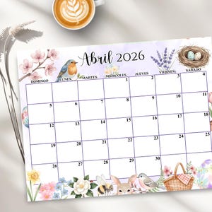 Pode incluir: Um calendário decorativo para abril de 2026, com um design em aquarela com ilustrações florais e de animais. O calendário inclui os dias da semana em espanhol, com ilustrações de pássaros, ninhos e coelhos. Uma xícara de café no fundo.