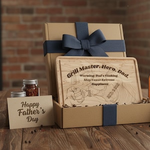 May include: A Father's Day gift set in a cardboard box with a blue ribbon. The set includes a wooden cutting board with the text "Grill Master. Hero. Dad." and a card that says "Happy Father's Day."