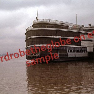 Puede incluir: Un barco grande de varios niveles atracado en un muelle. El barco tiene un exterior blanco y marrón con múltiples ventanas. La palabra "President" es visible en el costado del barco.