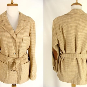 Może przedstawiać: Beżowo-brązowa, kratkowana marynarka z paskiem i brązowymi skórzanymi łatkami na łokciach.